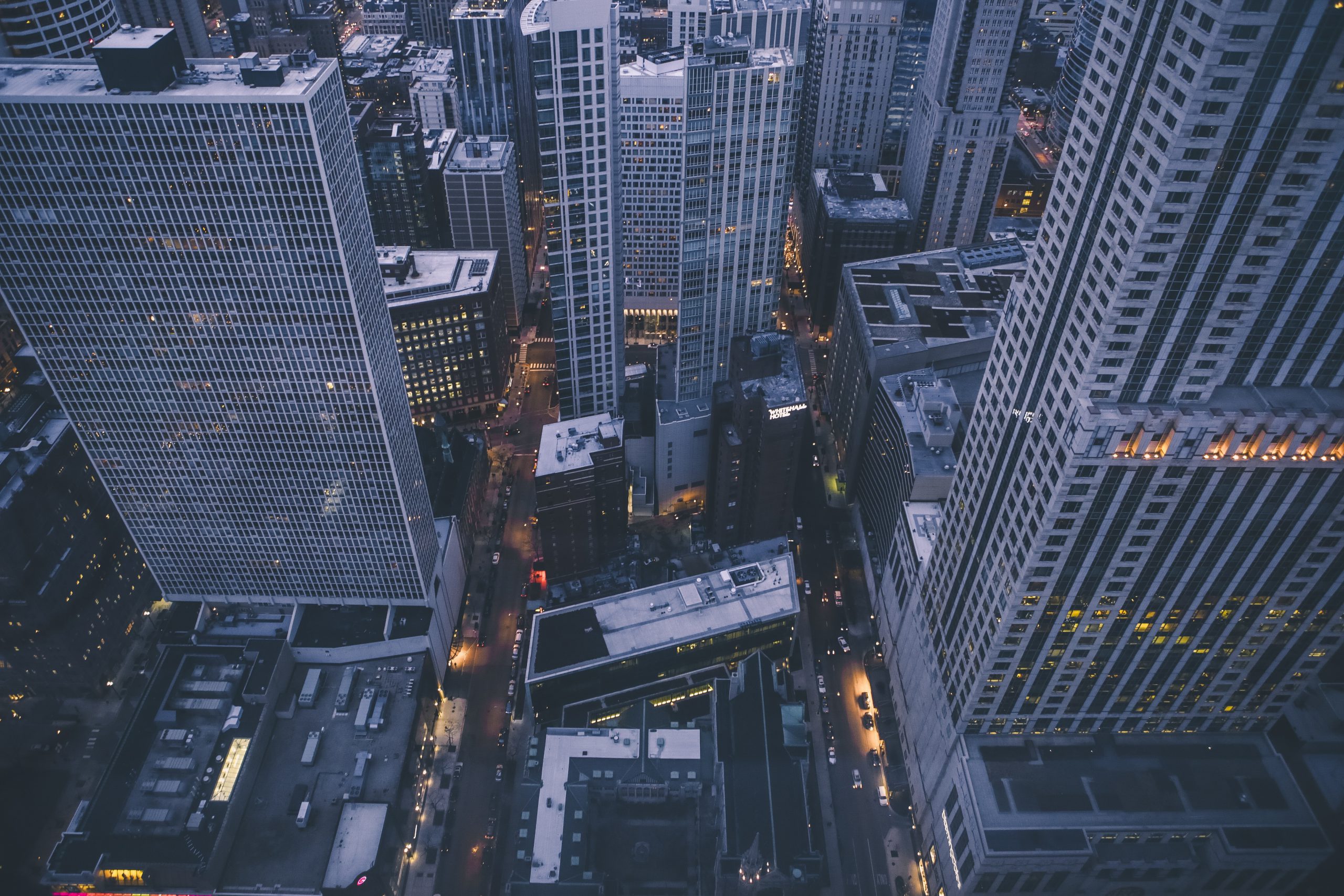 Aerial view of a cityscape with tall buildings and streets at dusk.